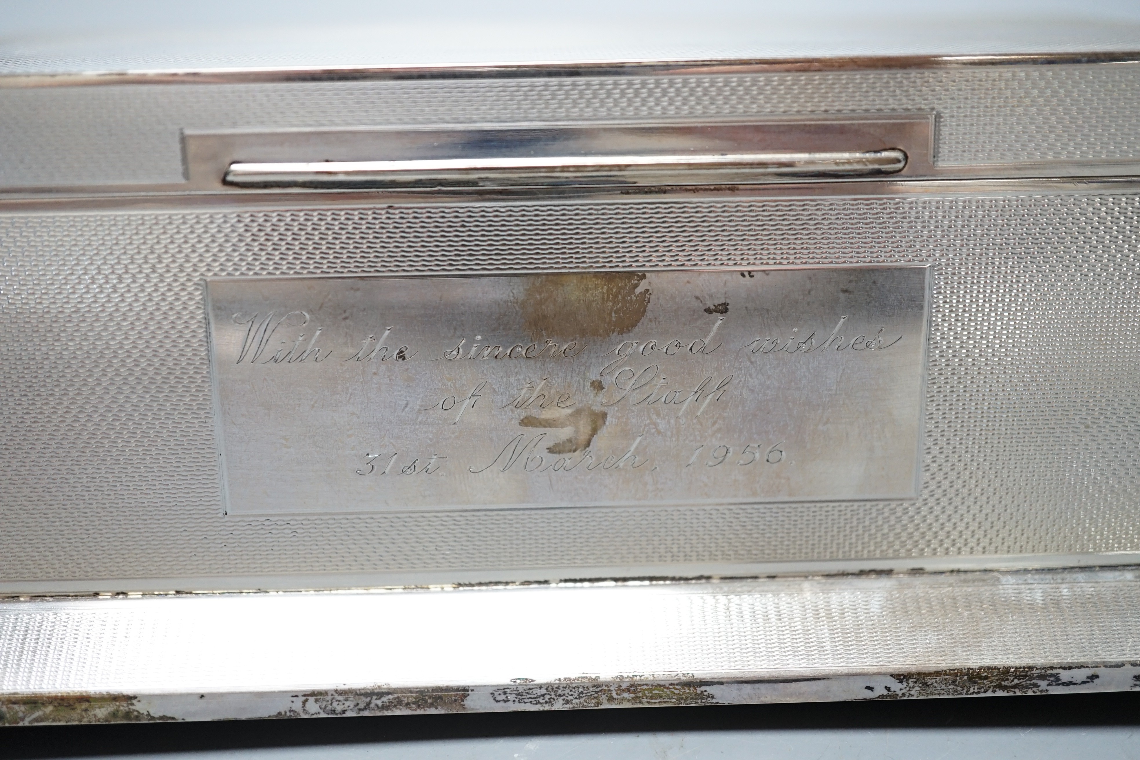 A George VI engine turned silver mounted rectangular cigarette box, Alexander Clark Co Ltd, Birmingham, 1948, with engraved inscription, on bracket feet, 20.4cm.